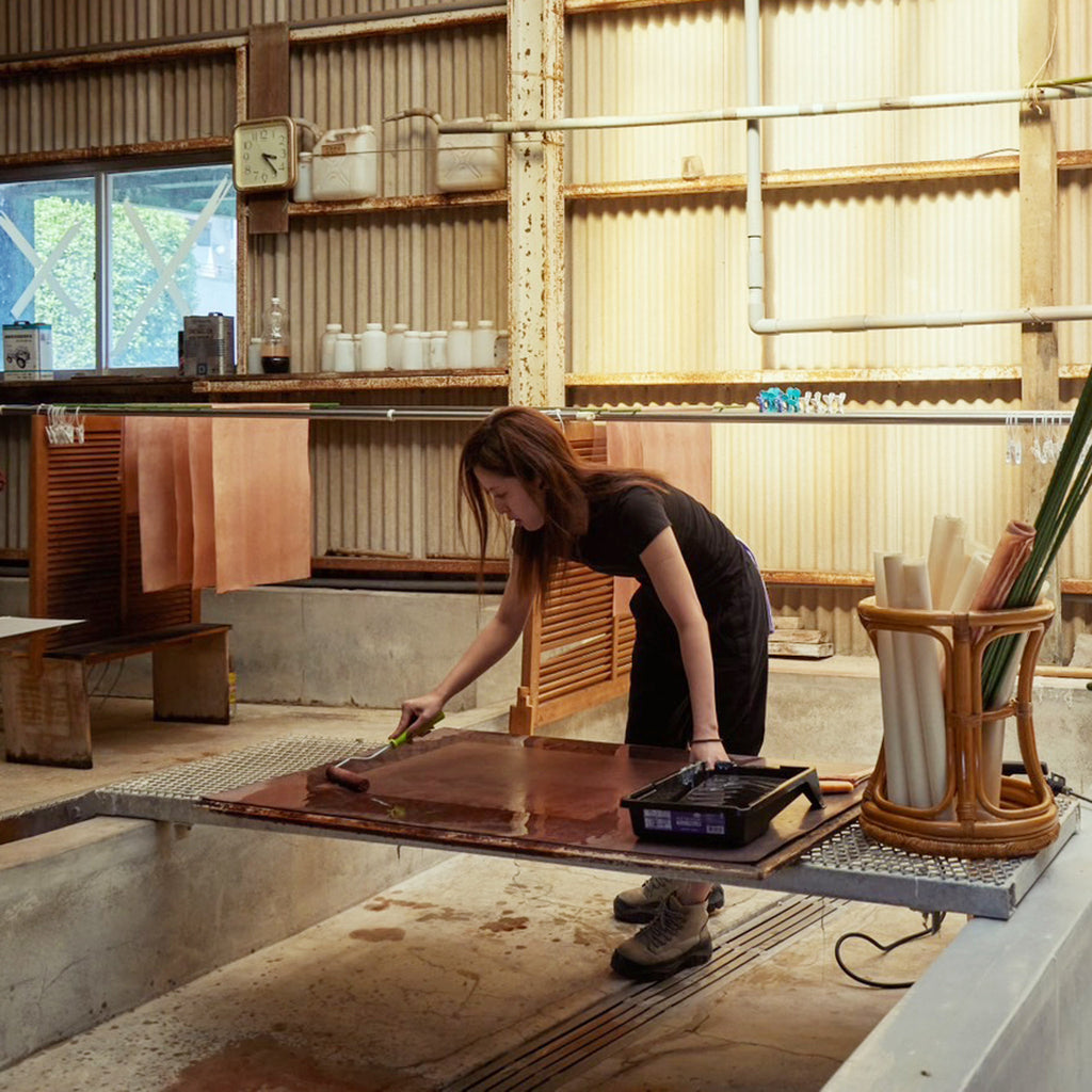 Japanese artisan applying kakishibu dye to washi paper for our Maru paper shades. 