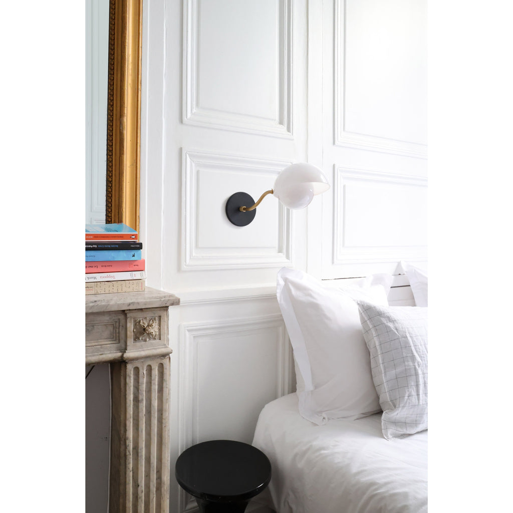 Noor Curve Sconce shown with a White Opal Acrylic Shade, Brass Arm and Matte Black Canopy.