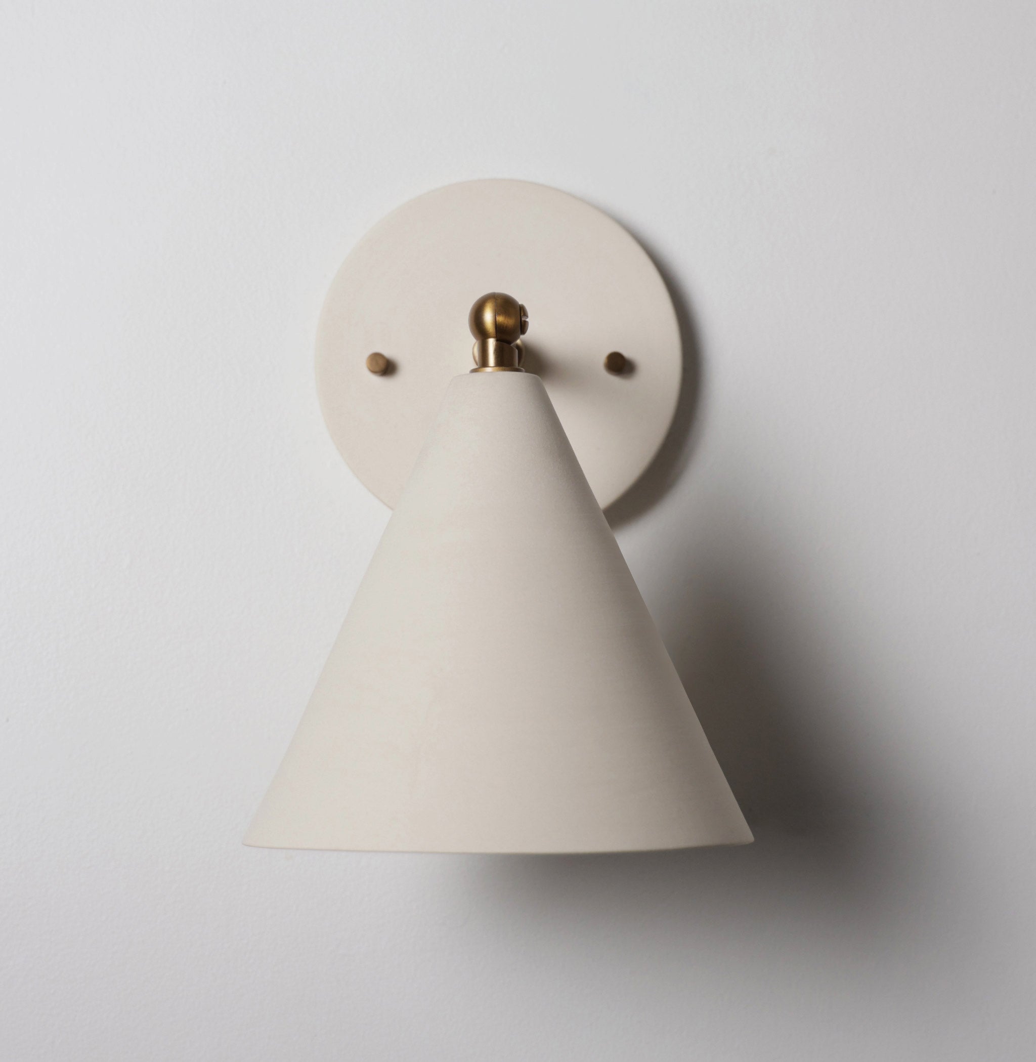 Petra Ceramic Sconce shown in Heirloom Brass with a 3" rod and Bone Ceramic canopy