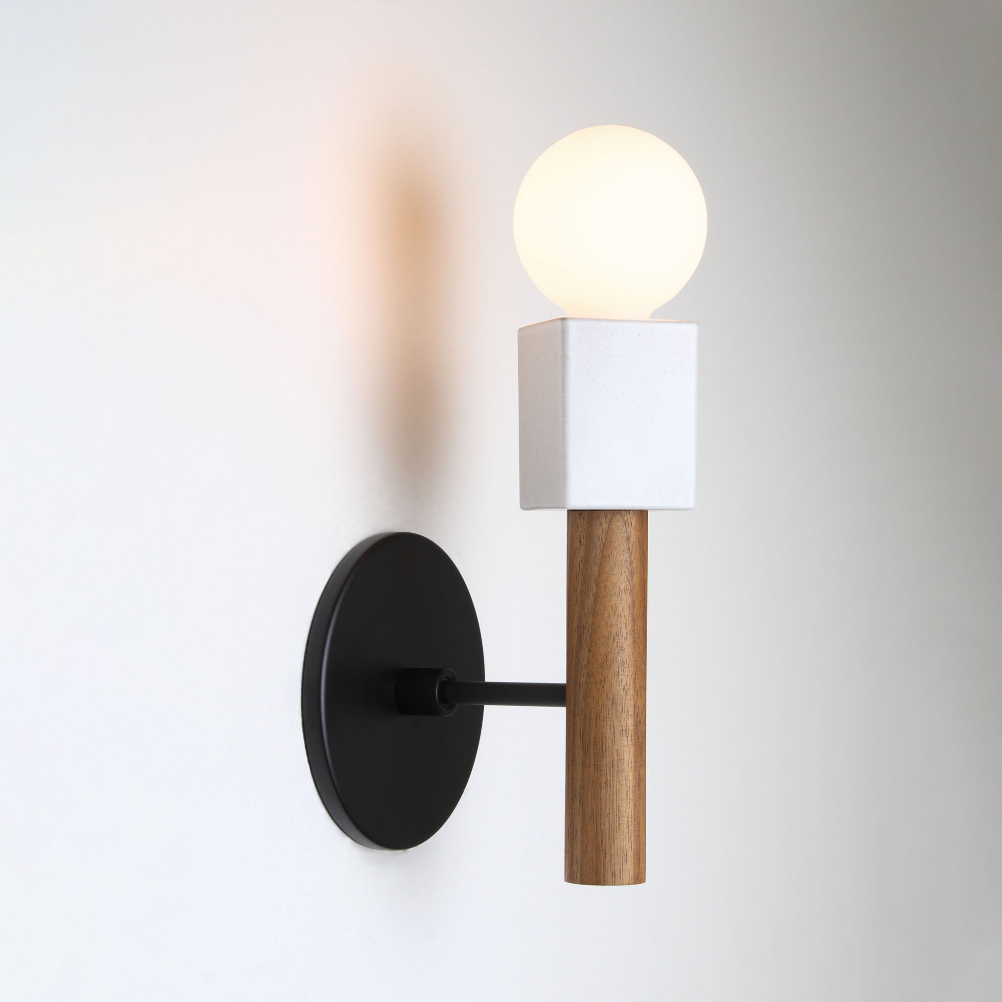 Seneca Sconce shown with a Matte Black metal canopy and Walnut