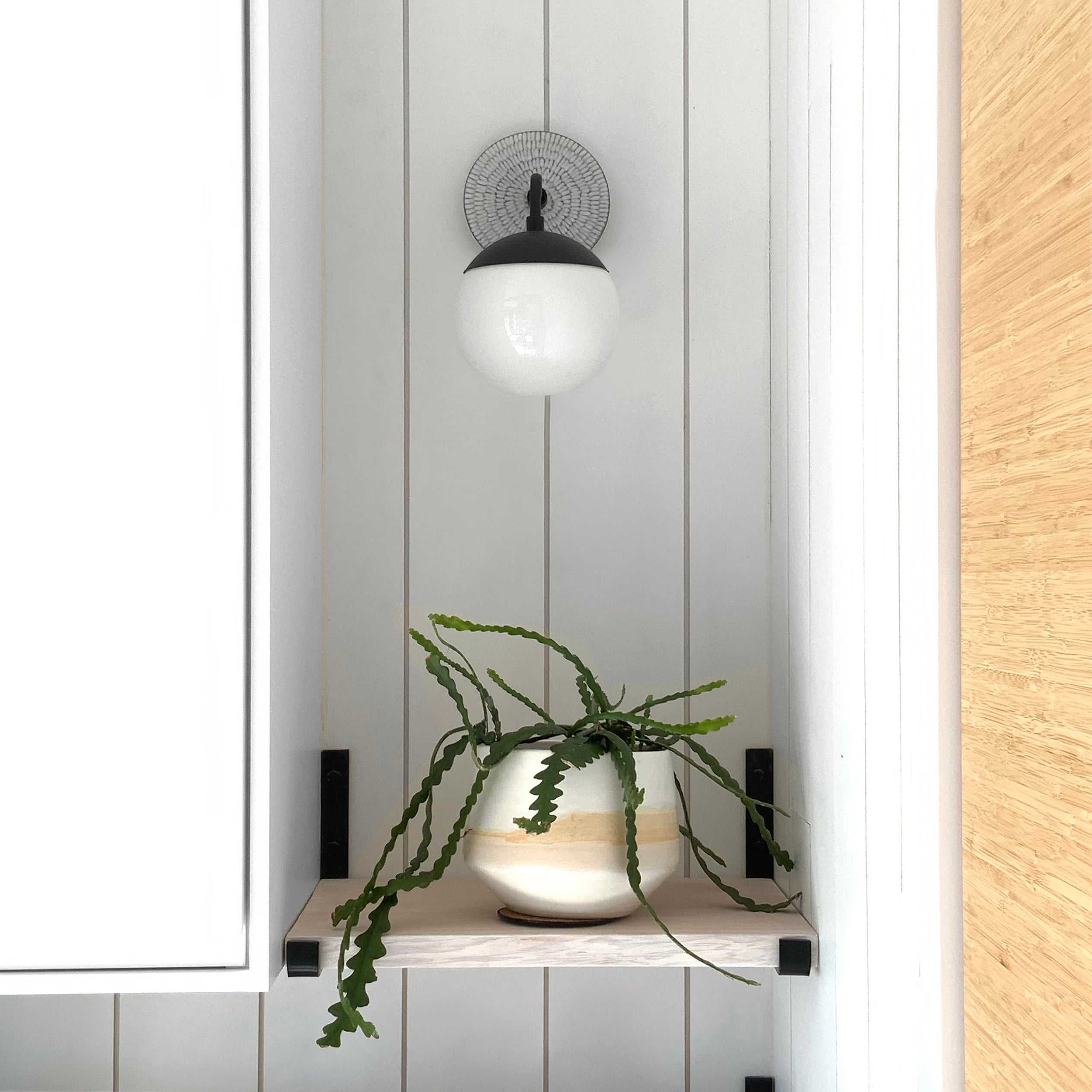    Alto Sconce 6" with Ceramic Canopy shown in Matte Black with a Brownstone White Sunflower Ceramic Canopy Pattern and an Opal 6" globe. Interior Design by Alison Vercruysse