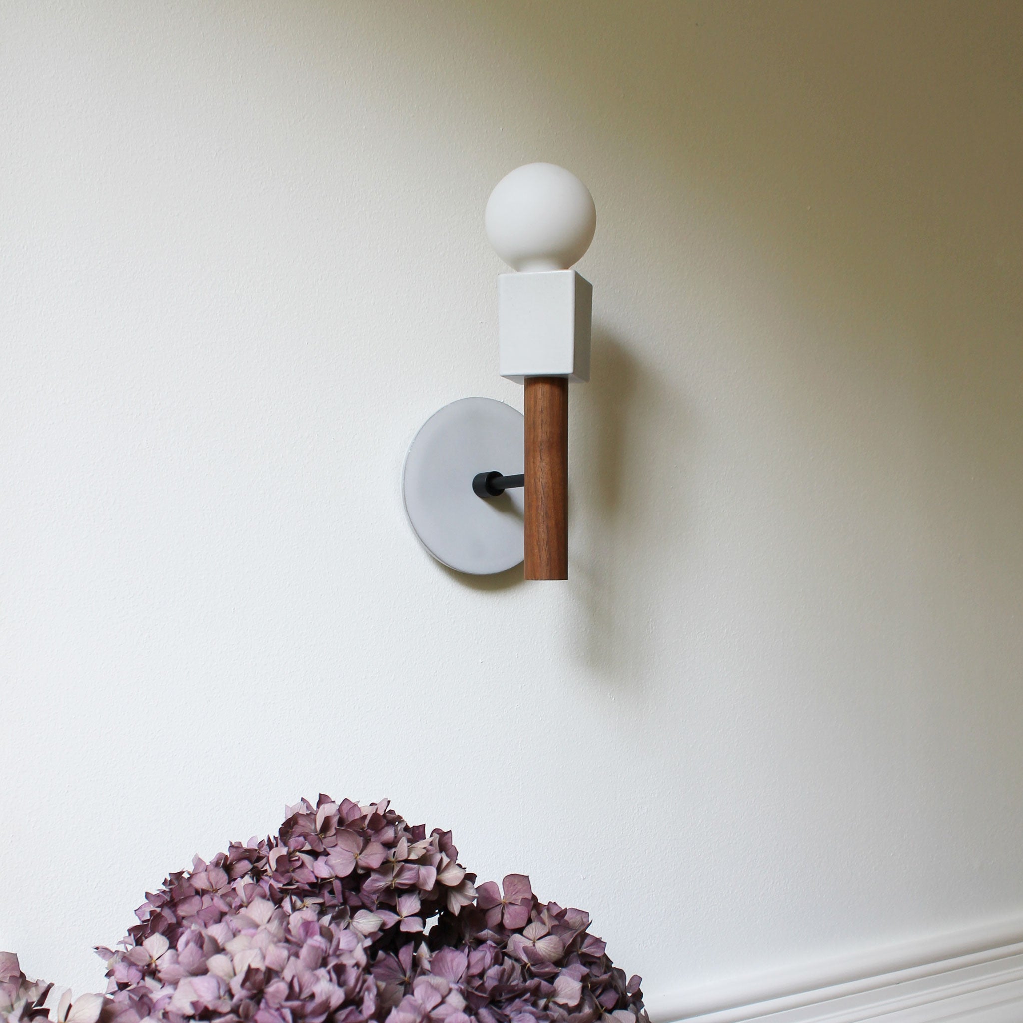 Seneca Sconce shown with a Swift pattern Brownstone White ceramic canopy, Matte Black, and Walnut